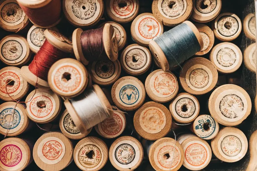 A collection of vintage wooden thread spools with colorful threads, perfect for sewing enthusiasts.