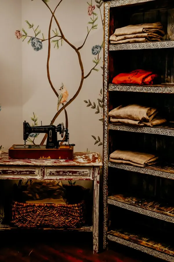 Cozy vintage sewing room featuring an antique sewing machine and wooden shelves with cloths.